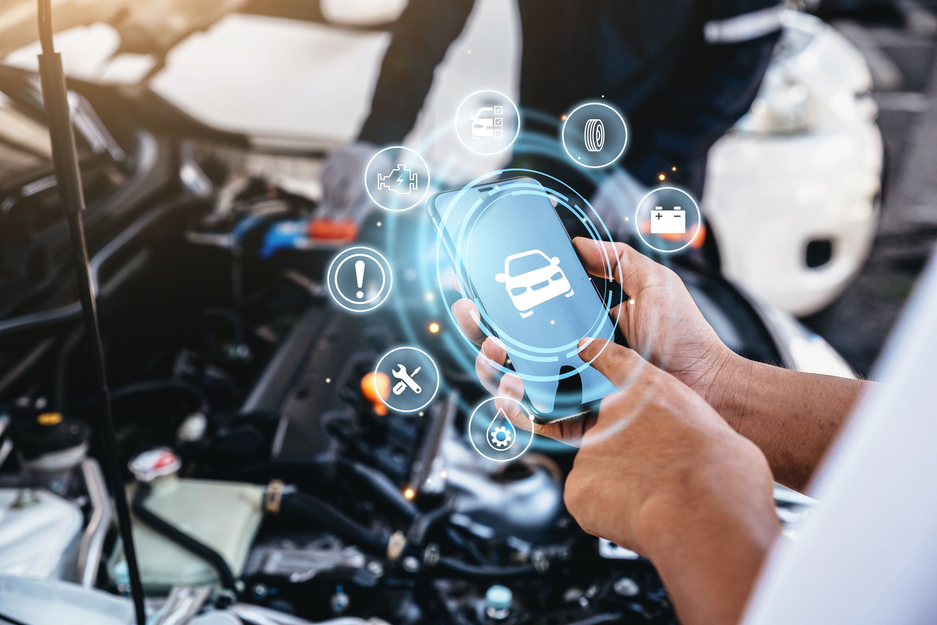 Mechanic using smart phone checking up on car engines parts for fixing and repair.